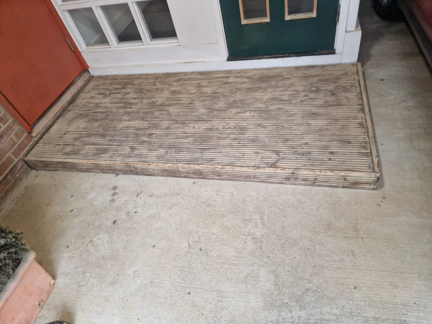 Worn coating across the existing entrance decking.