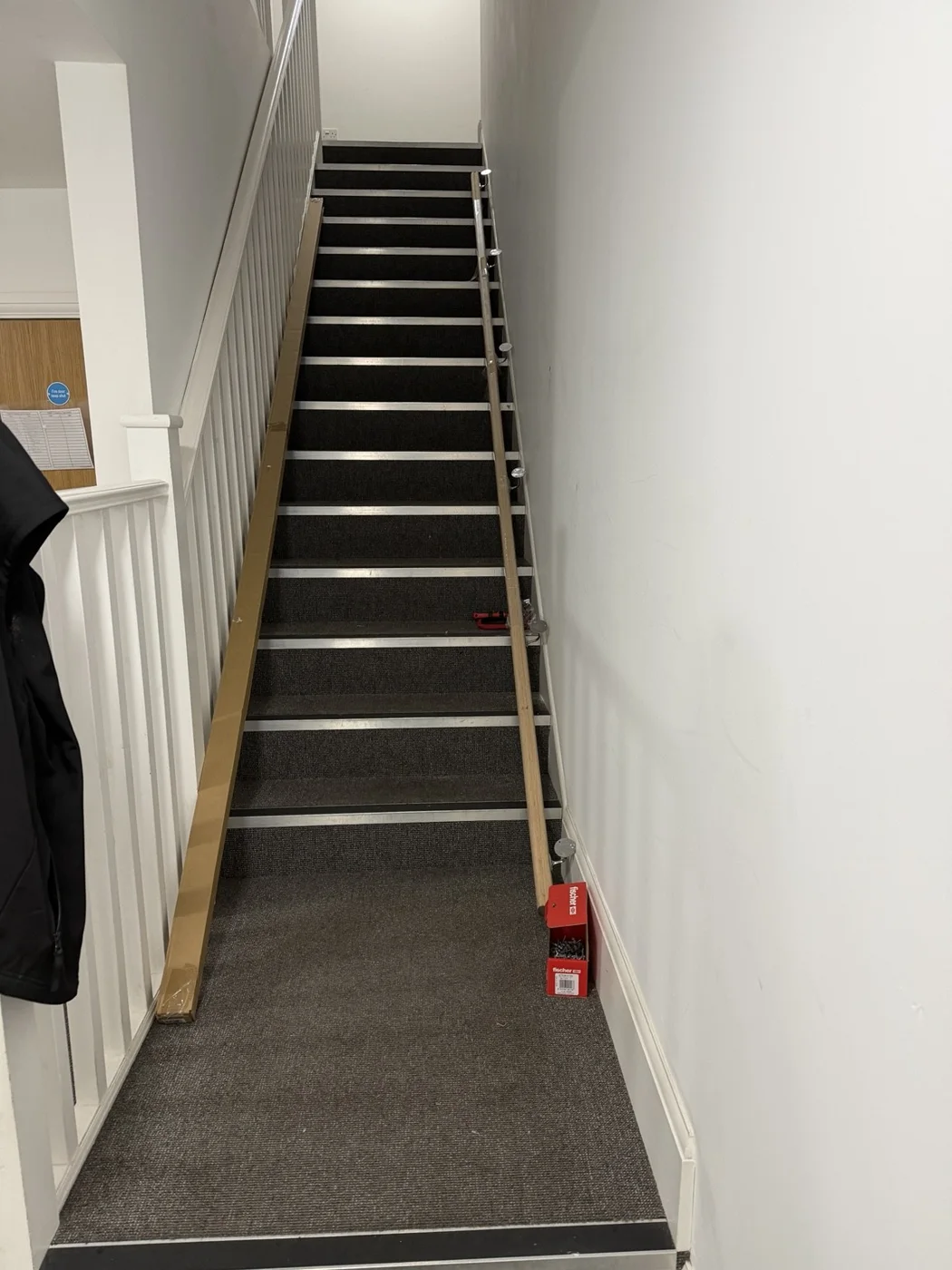 Timber rail and brackets laid out beside the stair flight during preparation.