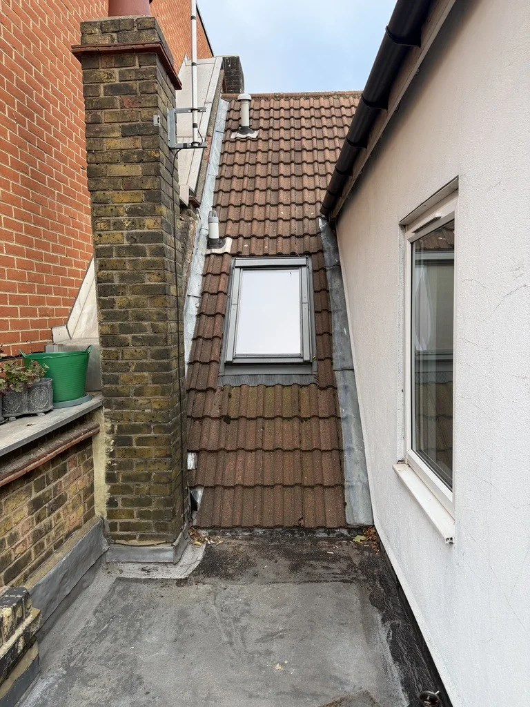 Existing rooflight, tiled slope and chimney junction before opening-up.
