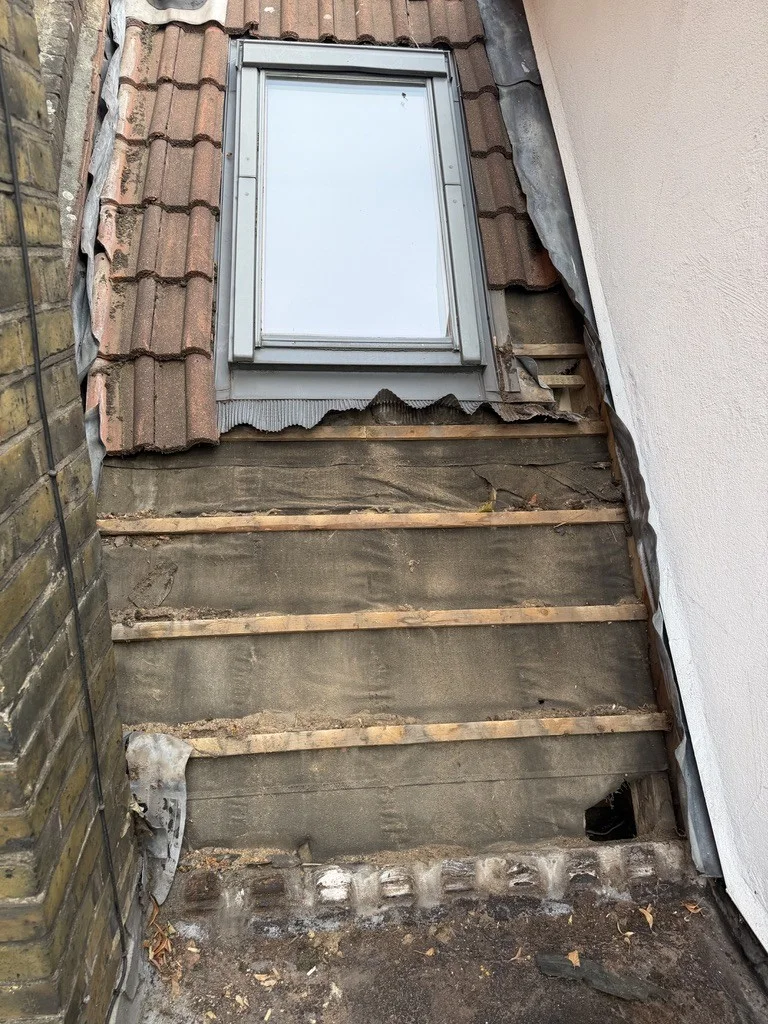 Roof tiles removed to expose the existing felt and battens below the rooflight.
